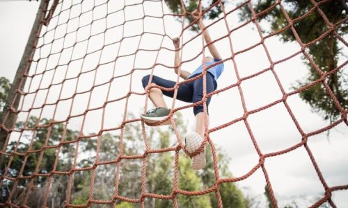 woman-climbing-net-during-obstacle-course-boot-camp_107420-97866